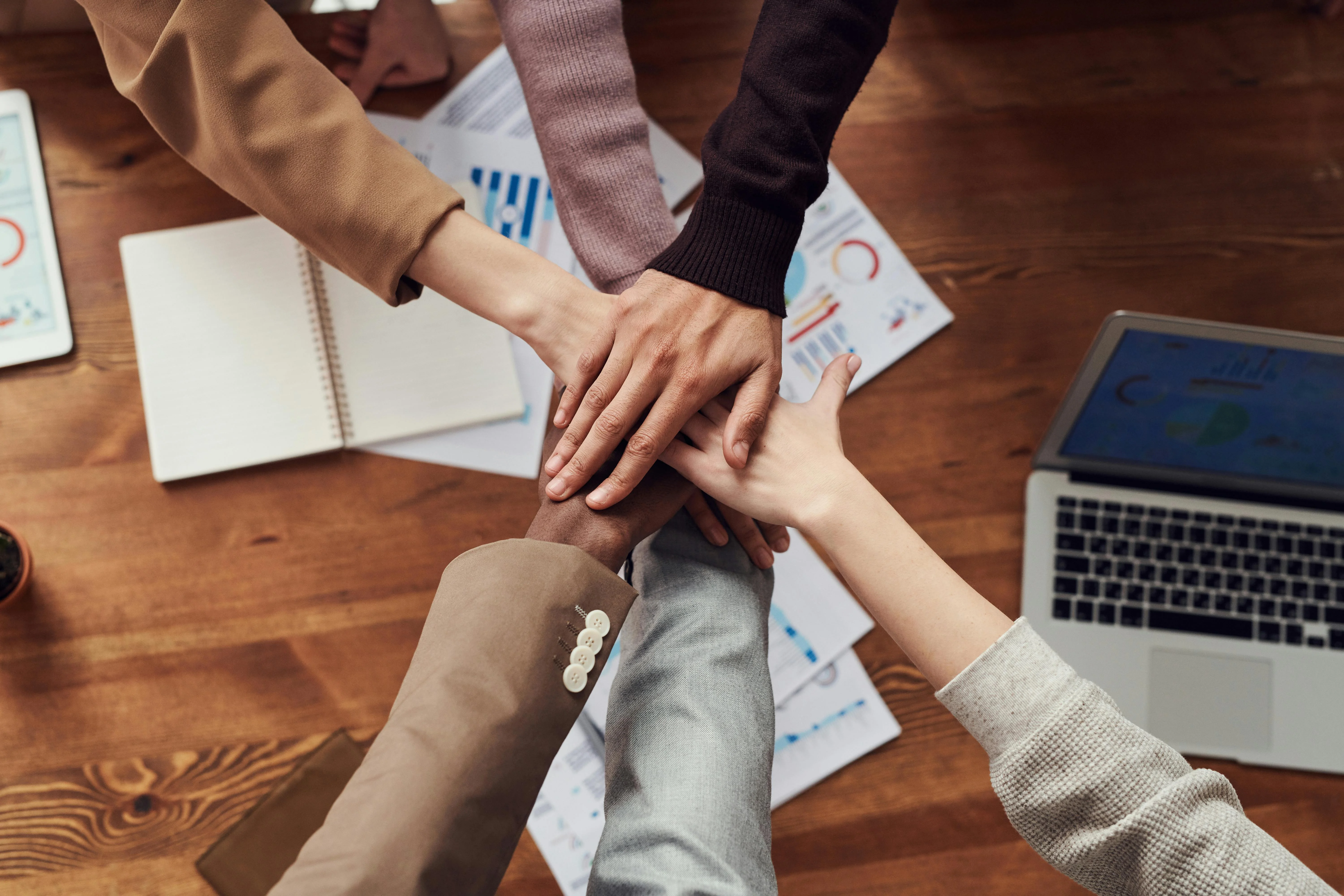Team members stacking hands together symbolizing collaborative workforce placement.